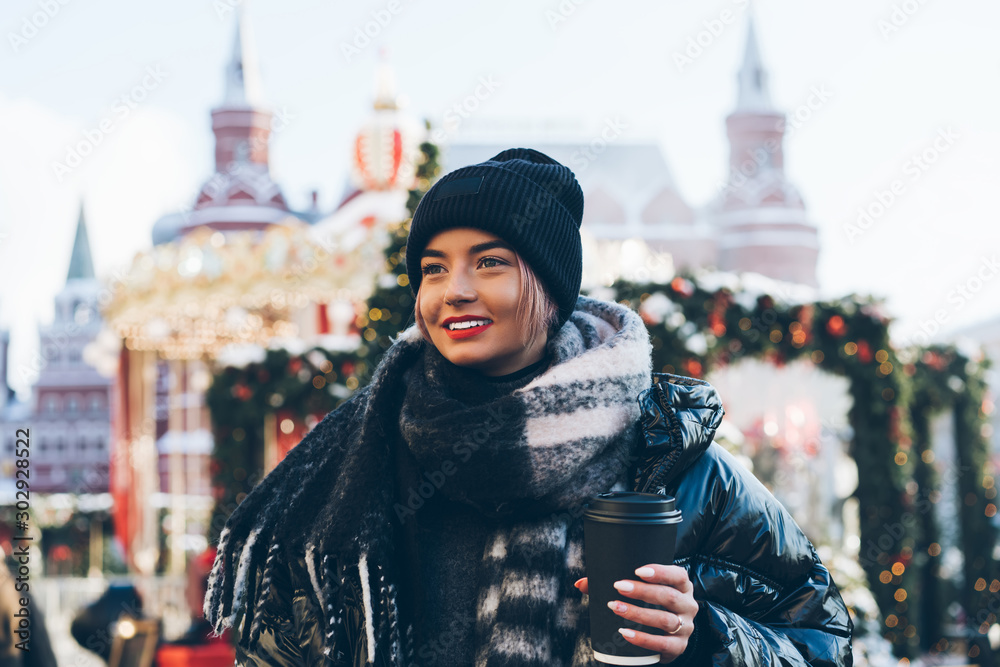 Young woman with takeaway coffee among garlands on street Young woman with takeaway coffee among garlands on street