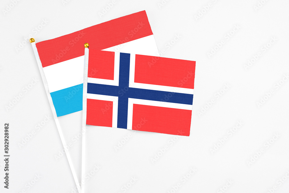 Bouvet Islands and Luxembourg stick flags on white background. High quality fabric, miniature national flag. Peaceful global concept.White floor for copy space.