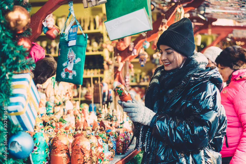 Positive female buying New Year souvenirs on fairground