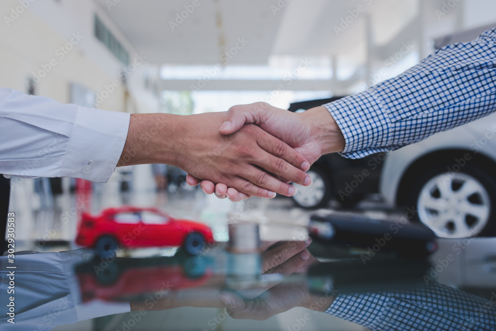 Agreements to buy new cars, new car loans or signing contracts with car keys and money in the foreground Blurred background for two business people standing hand in hand
