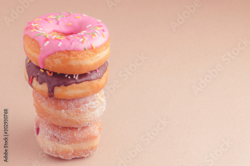 Fotografie Colorful sweet donuts stacked on brown background