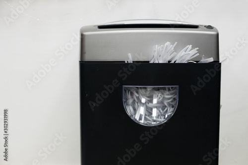 Gray black document shredder with paper inside on the white background.