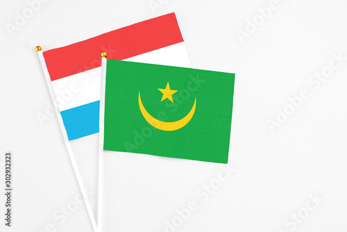 Mauritania and Luxembourg stick flags on white background. High quality fabric, miniature national flag. Peaceful global concept.White floor for copy space.