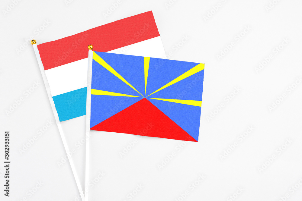 Reunion and Luxembourg stick flags on white background. High quality fabric, miniature national flag. Peaceful global concept.White floor for copy space.