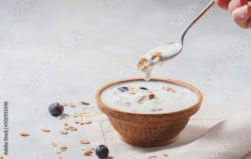 Homemade yogurt with granola and berries in a ceramic bowl on a light background. Concept healthy breakfast.