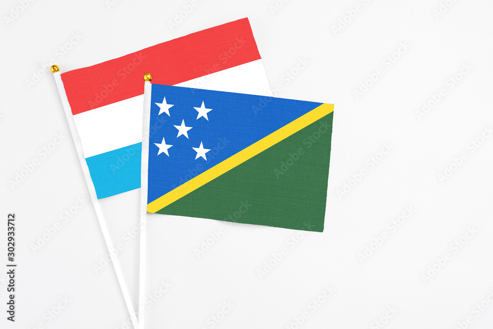Solomon Islands and Luxembourg stick flags on white background. High quality fabric, miniature national flag. Peaceful global concept.White floor for copy space. Solomon Islands and Luxembourg stick flags on white background. High quality fabric, miniature national flag. Peaceful global concept.White floor for copy space.