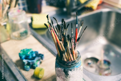 Creative workshop of the artist. Paint brushes in a jar. Many brushes for painting in one place