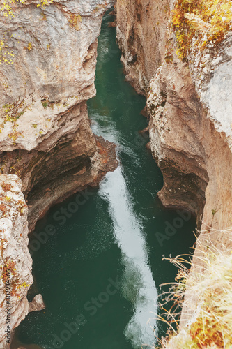 Gorge with a mountain river with a vibrant turquoise water between the rocks.