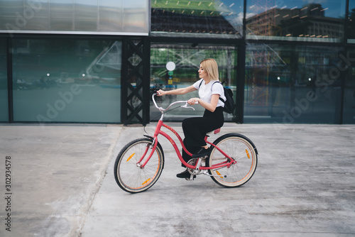 Adult blonde cyclist female riding bicycle in downtown