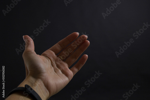 girl's hand on a black background stretched forward inviting or showing somewhere. Copy space