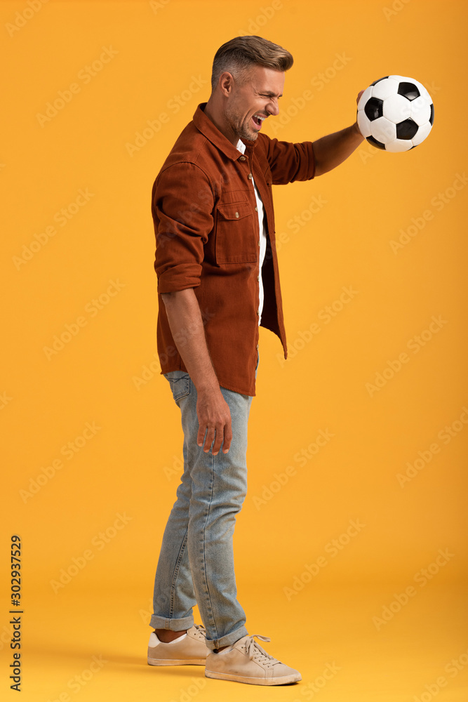 Fototapeta premium angry man holding football standing standing on orange