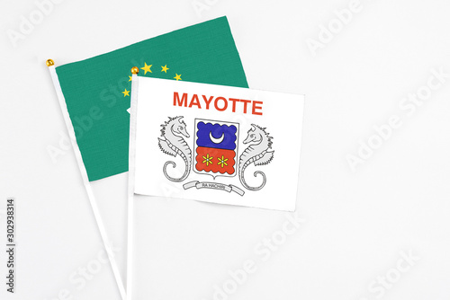 Mayotte and Macao stick flags on white background. High quality fabric, miniature national flag. Peaceful global concept.White floor for copy space.