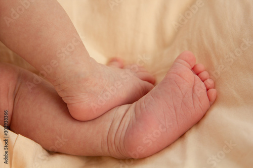 little cute feet of a newborn baby on a peach plaid. Newborn