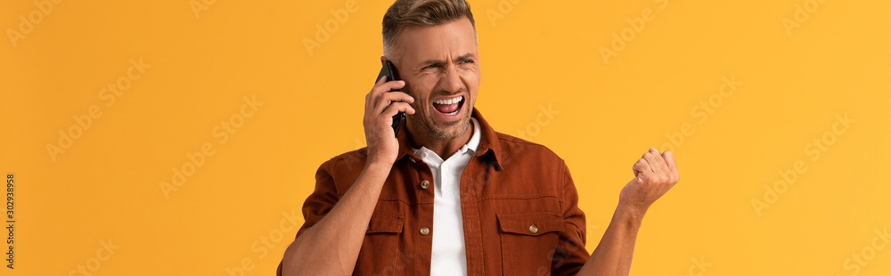 panoramic shot of angry man screaming while talking on smartphone isolated on orange - obrazy, fototapety, plakaty 