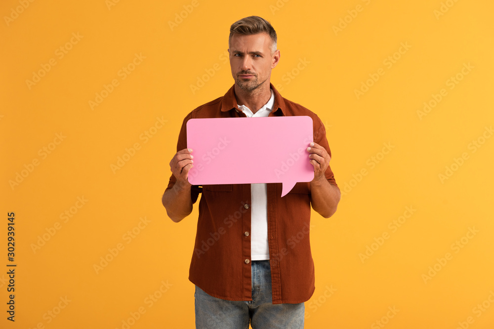 handsome man holding pink speech bubble isolated on orange handsome man holding pink speech bubble isolated on orange