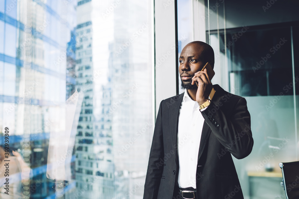 Fotografie Pensive ethnic businessman having phone call in office