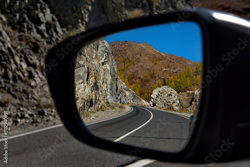 Russia. Mountain Altai. Reflection of the Chui tract in the side mirror of the car near the village of Maly Yaloman