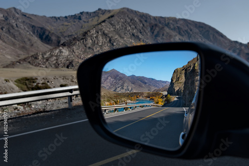 Russia. Mountain Altai. Reflection of the Chui tract in the side mirror of the car near the village of Maly Yaloman