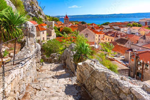 Sunny red roofs, Old city street with stone stairs and Church of St Michael in town and port Omis, popular tourist spot in Croatia photo