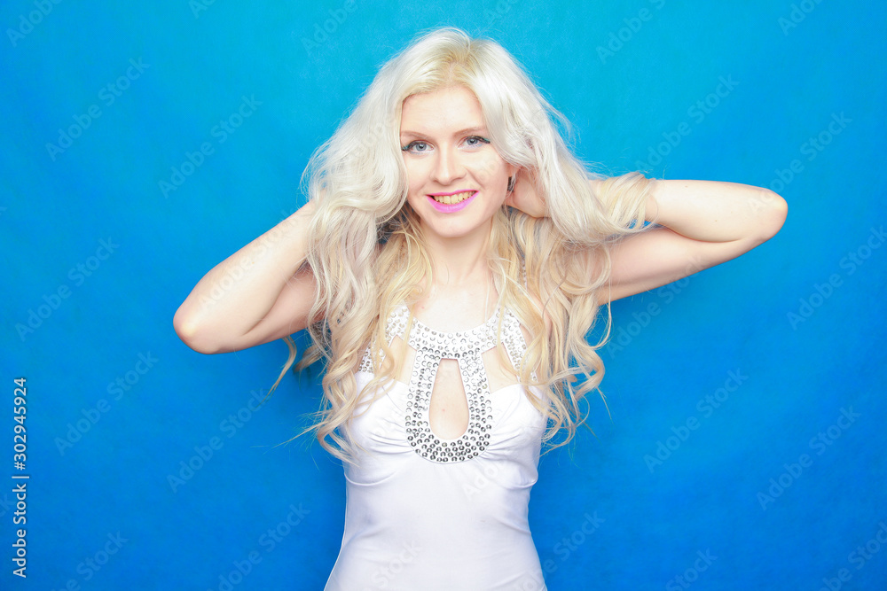 young blonde woman in white outfit on blue studio background. young blonde woman in white outfit on blue studio background.