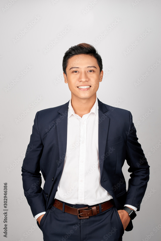 A young Asian man in suit put both hands in his pants pocket, isolated on a white background. A young Asian man in suit put both hands in his pants pocket, isolated on a white background.
