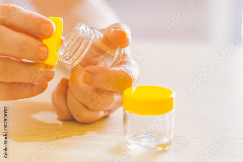 woman's old hand opening a small jar, glass pot jar  E