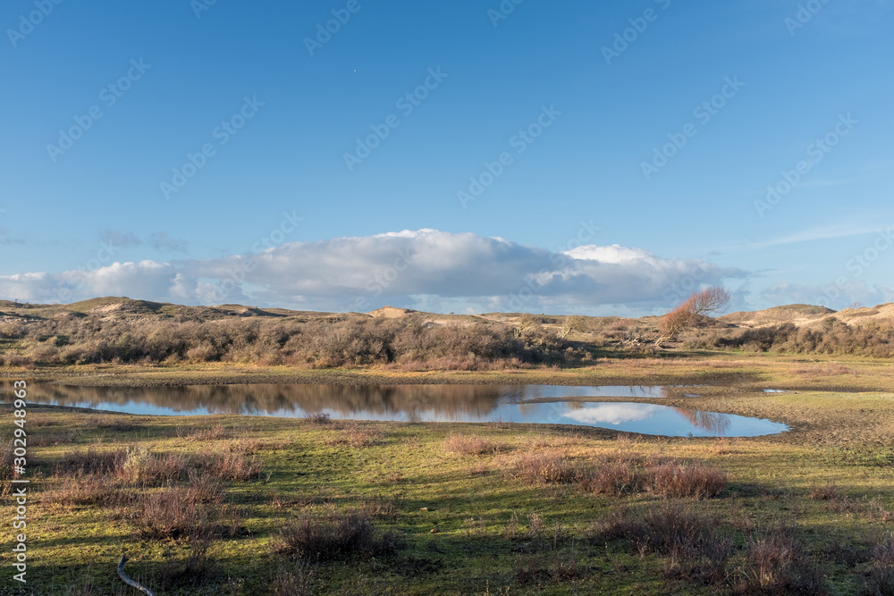 View of a dune lake with a light blue sky with clouds