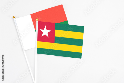 Togo and Madagascar stick flags on white background. High quality fabric  miniature national flag. Peaceful global concept.White floor for copy space.