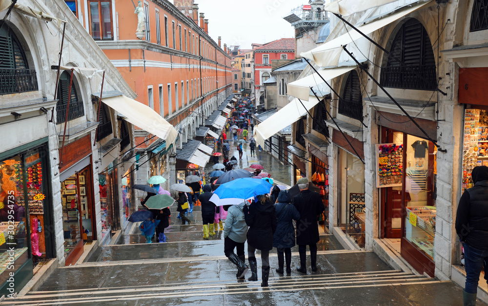People with umbrella in Rialto Bridge while raining in Venice in
