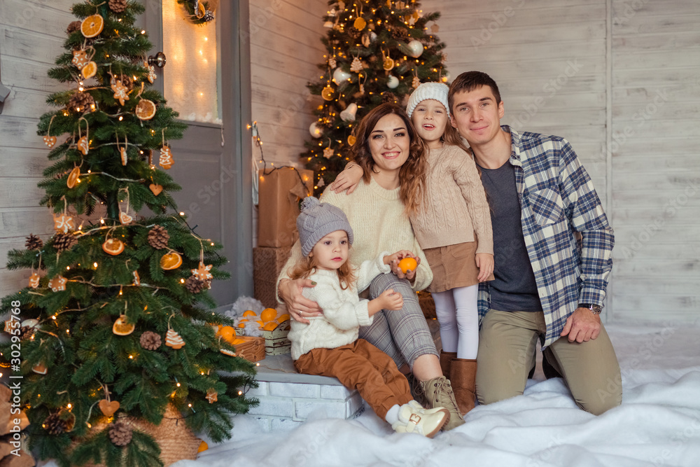 Happy family of 4 in anticipation of the New Year holiday having fun in the snow near the veranda of a wooden house. Happy family of 4 in anticipation of the New Year holiday having fun in the snow near the veranda of a wooden house.