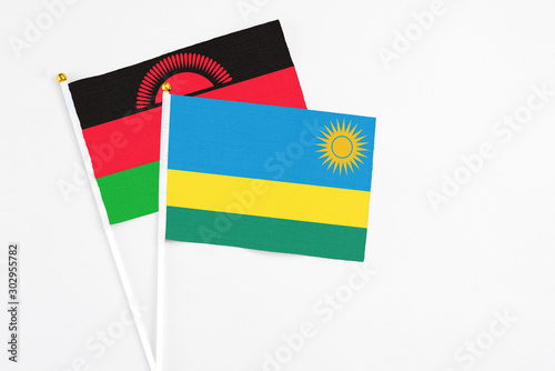 Rwanda and Malawi stick flags on white background. High quality fabric  miniature national flag. Peaceful global concept.White floor for copy space.