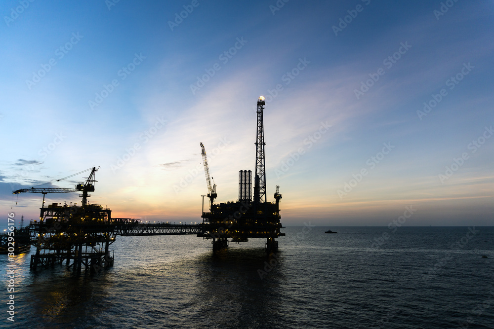 Silhouette of oil production platform during sunset