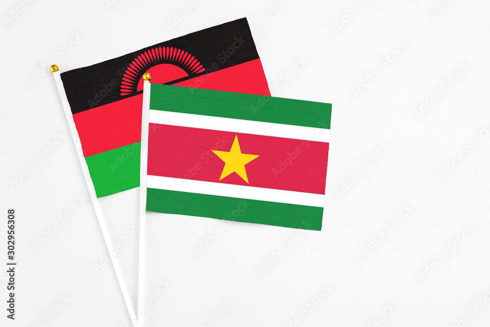 Suriname and Malawi stick flags on white background. High quality fabric, miniature national flag. Peaceful global concept.White floor for copy space.