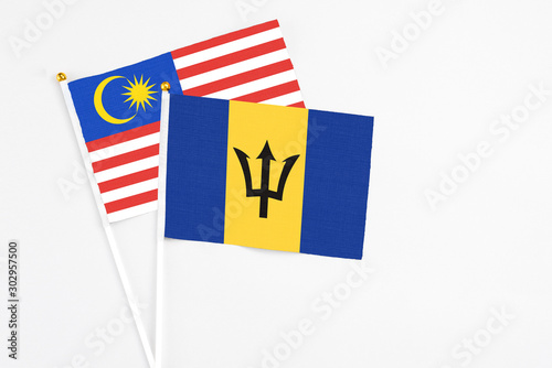 Barbados and Malaysia stick flags on white background. High quality fabric, miniature national flag. Peaceful global concept.White floor for copy space.