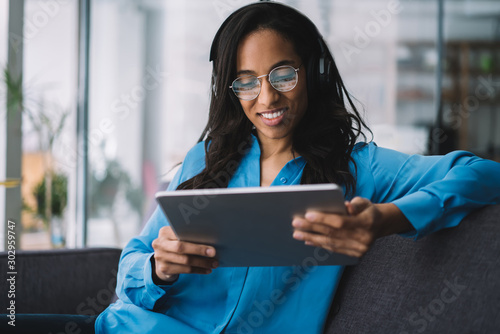 Smiling black brunette woman in headphones having rest with tablet