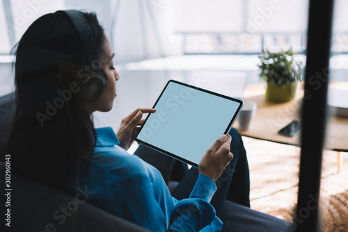 Young black woman surfing tablet while listening to music at home