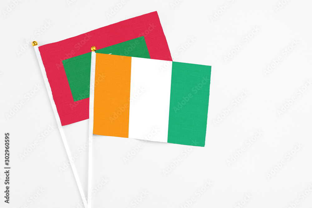 Cote D'Ivoire and Maldives stick flags on white background. High quality fabric, miniature national flag. Peaceful global concept.White floor for copy space.