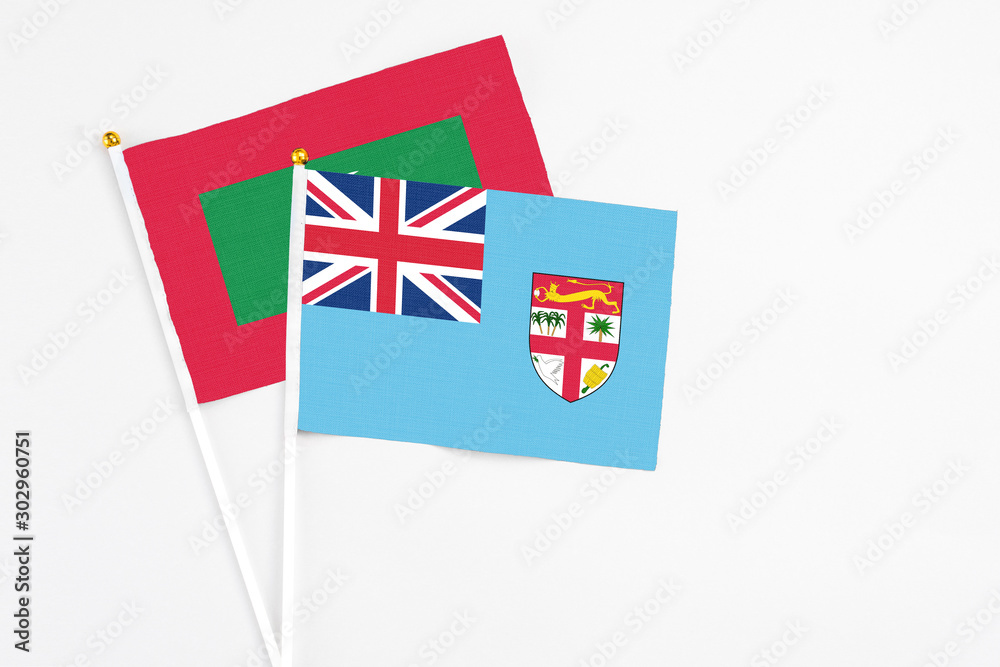 Fototapeta premium Fiji and Maldives stick flags on white background. High quality fabric, miniature national flag. Peaceful global concept.White floor for copy space.