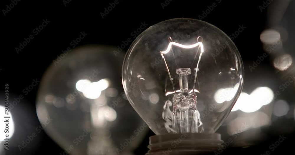 The incandescent lamp with a tungsten filament wobbles on the wire. The light flashes . Light from a light bulb. Bulb close-up.