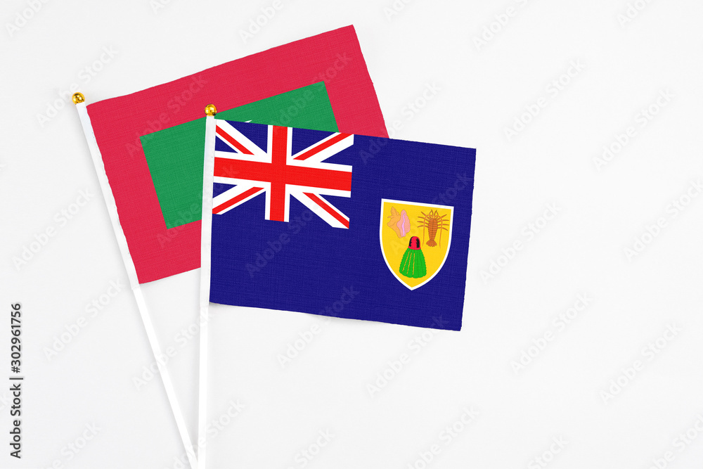 Fototapeta premium Turks And Caicos Islands and Maldives stick flags on white background. High quality fabric, miniature national flag. Peaceful global concept.White floor for copy space.