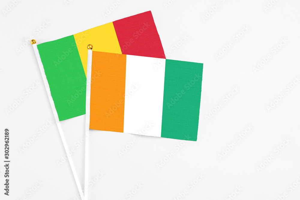 Cote D'Ivoire and Mali stick flags on white background. High quality fabric, miniature national flag. Peaceful global concept.White floor for copy space. Cote D'Ivoire and Mali stick flags on white background. High quality fabric, miniature national flag. Peaceful global concept.White floor for copy space.
