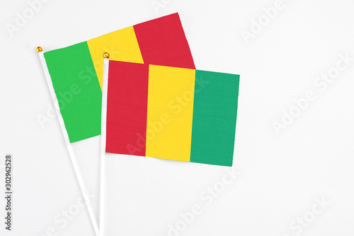 Guinea and Mali stick flags on white background. High quality fabric  miniature national flag. Peaceful global concept.White floor for copy space.