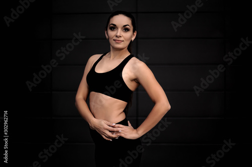 Young woman with fit body dressed black sportweart trainig workout outdoors against the street wall.  Style girl do morning activity