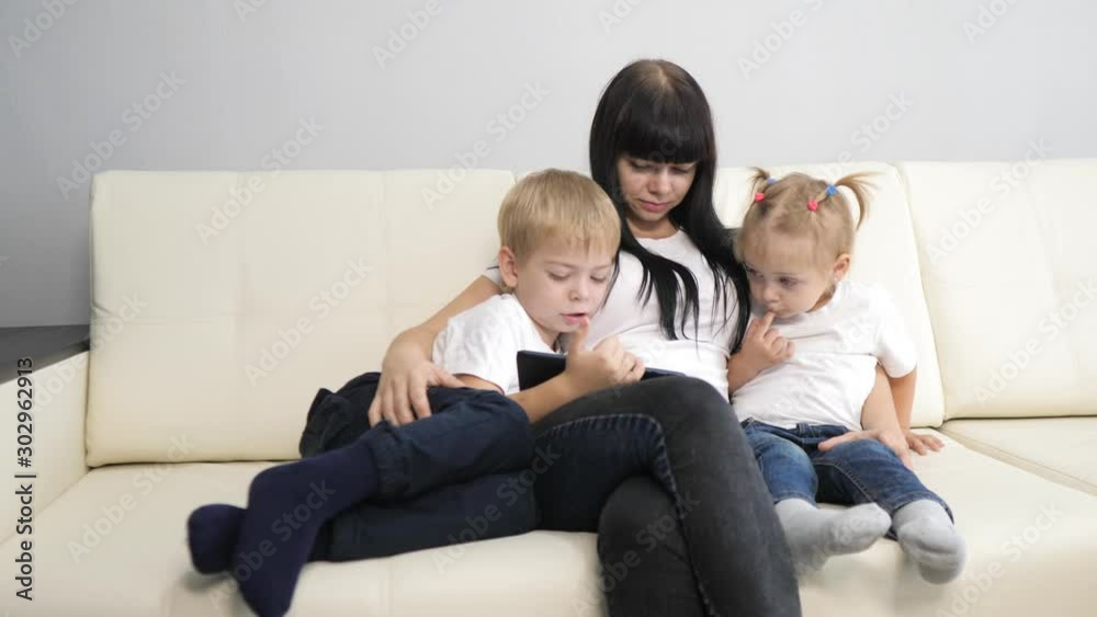 happy family a with digital tablet teamwork leisure concept. mom and children watch an online movie series on a digital tablet. mother lifestyle and little boy and girl watch cartoons on a digital happy family a with digital tablet teamwork leisure concept. mom and children watch an online movie series on a digital tablet. mother lifestyle and little boy and girl watch cartoons on a digital