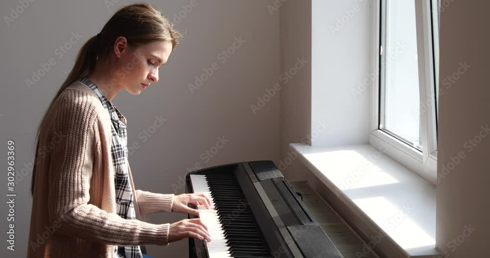Pretty teenage girl playing piano at home