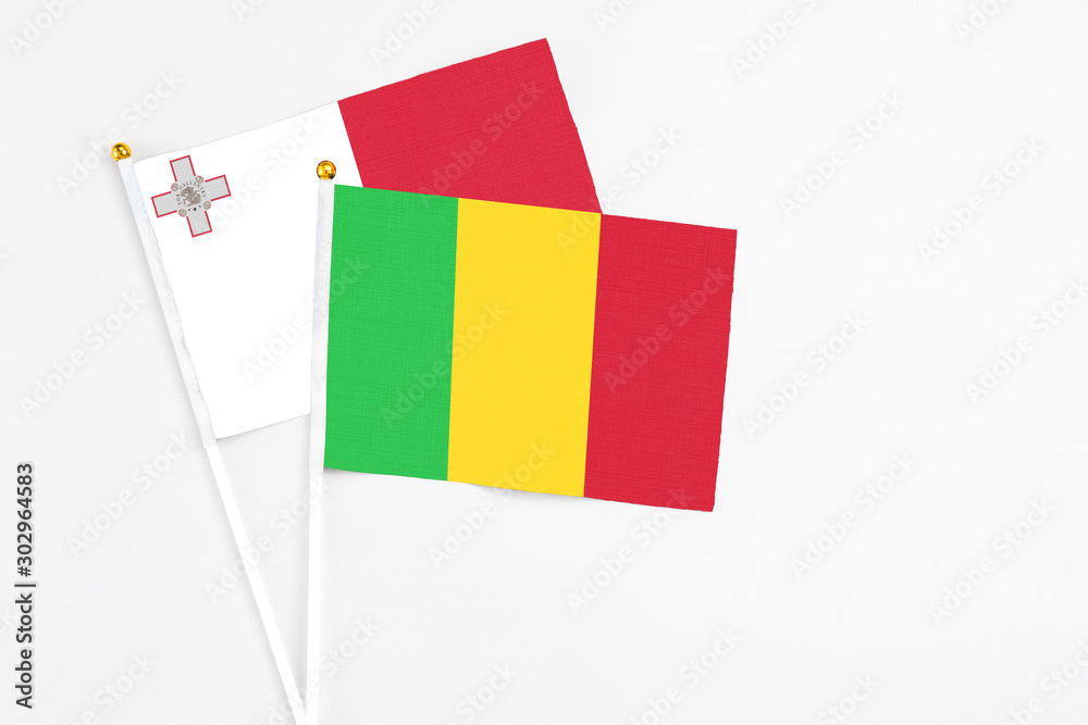 Mali and Malta stick flags on white background. High quality fabric, miniature national flag. Peaceful global concept.White floor for copy space. Mali and Malta stick flags on white background. High quality fabric, miniature national flag. Peaceful global concept.White floor for copy space.
