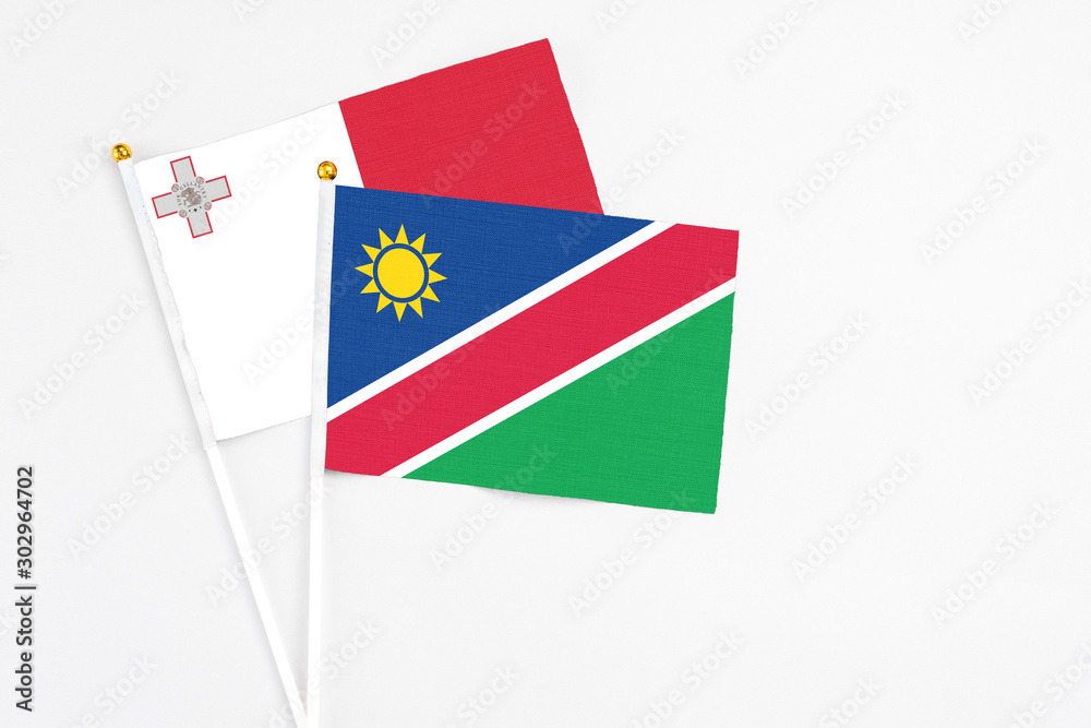 Namibia and Malta stick flags on white background. High quality fabric, miniature national flag. Peaceful global concept.White floor for copy space.