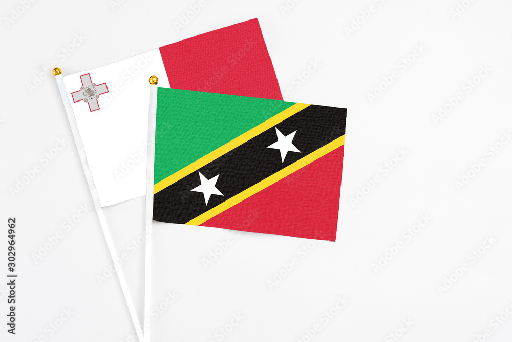 Saint Kitts And Nevis and Malta stick flags on white background. High quality fabric, miniature national flag. Peaceful global concept.White floor for copy space. Saint Kitts And Nevis and Malta stick flags on white background. High quality fabric, miniature national flag. Peaceful global concept.White floor for copy space.