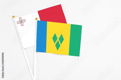 Saint Vincent And The Grenadines and Malta stick flags on white background. High quality fabric, miniature national flag. Peaceful global concept.White floor for copy space.