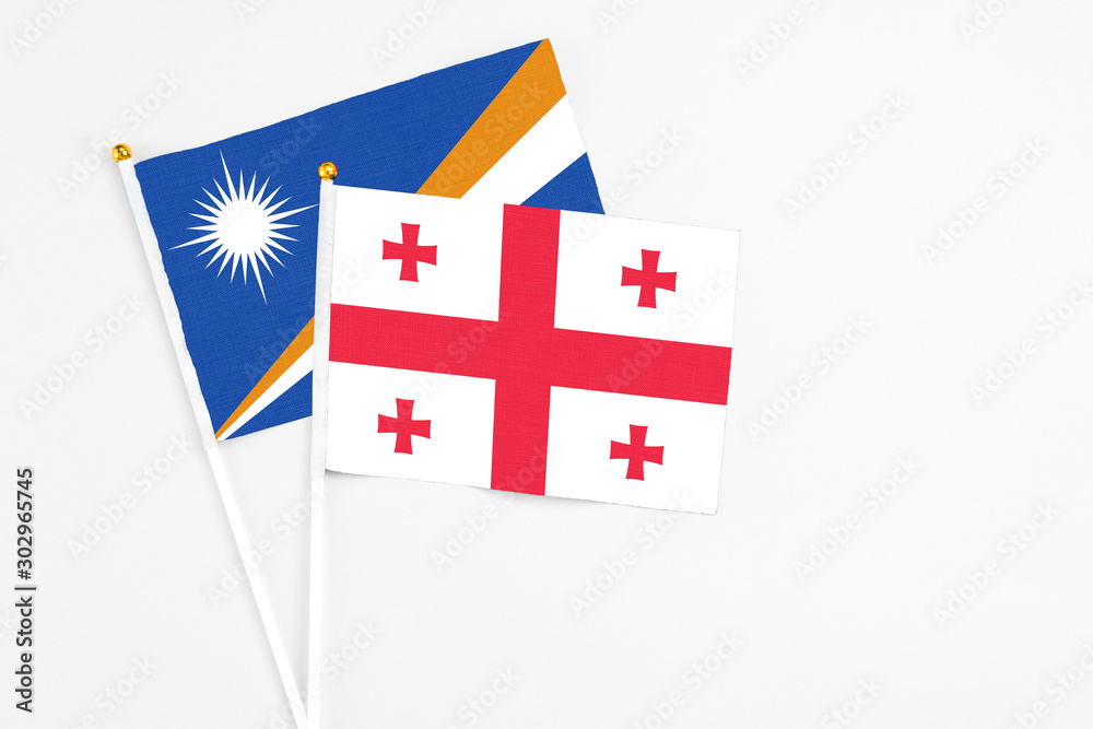 Georgia and Marshall Islands stick flags on white background. High quality fabric, miniature national flag. Peaceful global concept.White floor for copy space.
